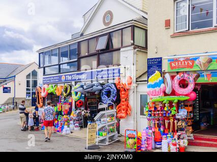 In einem Geschäft von The Cobb in Lyme Regis an der Jurassic Coast in Dorset, Südengland, werden am Straßenrand bunte Schlauchboote und Strandspielzeug ausgestellt Stockfoto