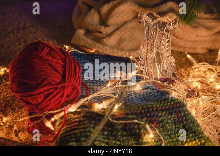 Strickartikel, eine Wollkugel und eine Vase in Form eines Kristallschabers am Weihnachtsbaum Stockfoto