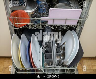 Offene Spülmaschine mit sauberem Geschirr, Utensilien und Töpfen Stockfoto