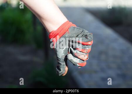 Unschärfe-Unschärfe-Gestik. Schmutzige und undichte Handschuhe getragen. Handflächen in abgenutzten Arbeitshandschuhen öffnen, Schutz vor Beschädigungen während des Betriebs, Nahaufnahme Stockfoto