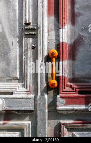 Unschärfe-Empfänger mit braunem Vintage-Telefon an der Grifftür. Geschlossene Holztür Gebäudeeingang auf der Straße mit Kopierplatz an der Wand. Alte Türen. Vertikal Stockfoto