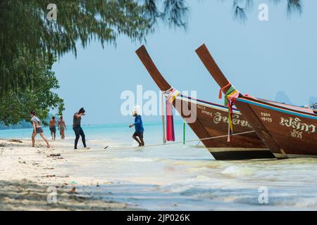 Strand auf der Insel Koh Kradan in der Andamanensee. Traditionelle thailändische Boote und Touristen, die auf der paradiesischen Insel kreuzen und schwimmen Stockfoto