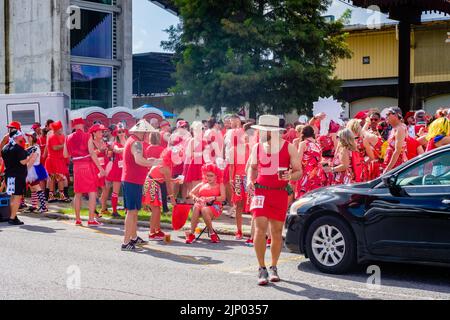 NEW ORLEANS, LA, USA - 13. AUGUST 2022: Große kostümierte Menschenmassen versammelten sich vor dem Crescent Park zum jährlichen Red Dress Run Stockfoto