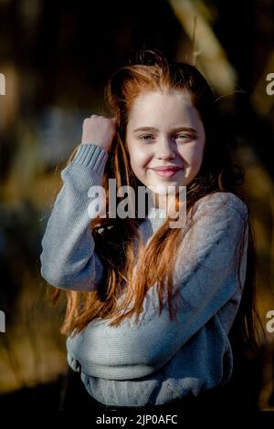 Ein langhaariges rothaariges Teenager-Mädchen im Park. Stockfoto