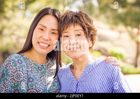 Außenportrait einer glücklichen chinesischen Mutter und Tochter. Stockfoto