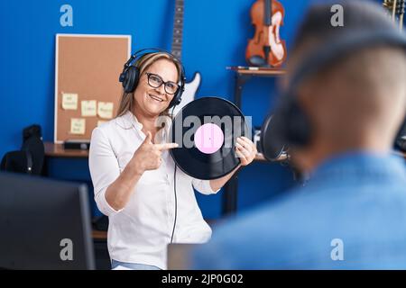 Mann und Frau Musiker hören Musik mit Vinyl-Schallplatte im Musikstudio Stockfoto