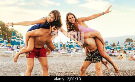 Gruppe von Millennials-Freunden Spaß am Strand Huckepack zusammen - Sommer junge Menschen Lifestyle-Konzept Stockfoto