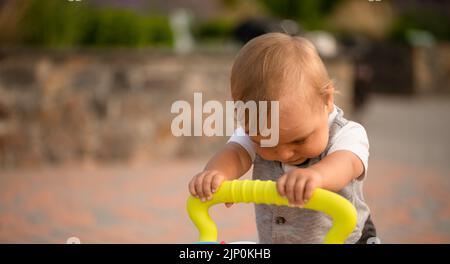 Ein kleiner Junge lernt mit Hilfe eines Rollstuhls laufen. Stockfoto