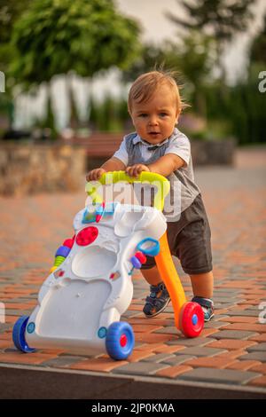 Ein kleiner Junge lernt mit Hilfe eines Rollstuhls laufen. Stockfoto