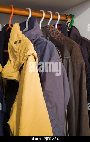 Winterjacken auf Kleiderbügeln in einem Aufbewahrungsschrank. Stockfoto