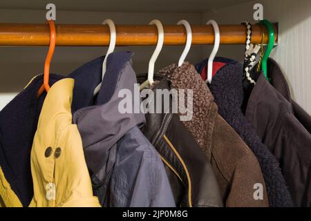 Winterjacken werden auf Kleiderbügeln in einem Kleiderschrank aufbewahrt. Stockfoto