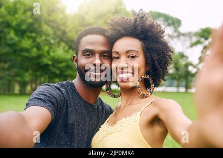 Sie sind ein Bilderbuch-Paar. Beschnittenes Porträt eines liebevollen jungen Paares, das Selfies macht, während er einige Zeit im Park verbringt. Stockfoto