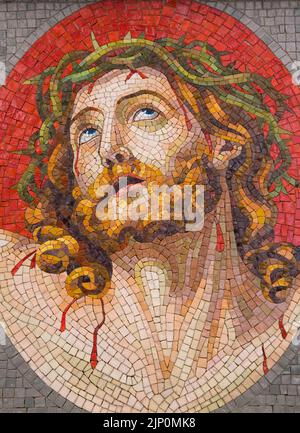 Mosaik aus kleinen Keramikfliesen, die Jesus mit einer Dornenkrone auf dem Denkmal auf einem Friedhof darstellen. Stockfoto