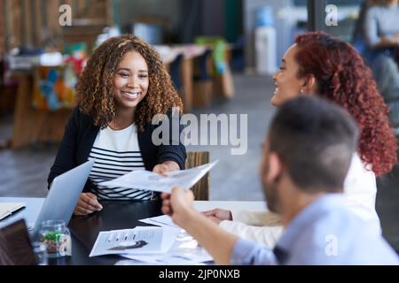 Großartige Arbeit. Eine attraktive junge Geschäftsfrau, die einem männlichen Kollegen während einer Sitzung im Sitzungssaal einen Papierkram übergab. Stockfoto