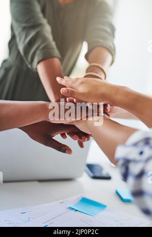 Vereint in der Erfeilung der Arbeit. Eine Gruppe von unkenntlichen Geschäftsfrauen, die sich im Büro die Hände übereinander stapeln. Stockfoto