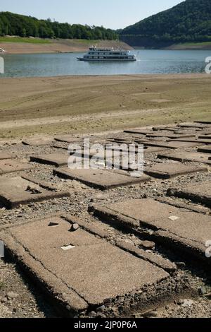 Bringhausen, Deutschland. 11. August 2022. Ein Schiff am Edersee passiert den alten, trockenen Bringhäuser Friedhof in der Bringhäuser Bucht. Das größte Hessische Reservoir ist aufgrund der Dürre und der Wasserabgabe an die Weser-Navigation nur zu 20 Prozent voll. Quelle: Uwe Zucchi/dpa/Alamy Live News Stockfoto