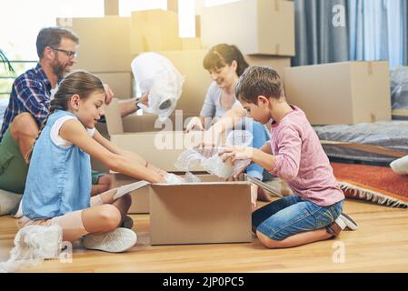 Teamarbeit macht es zu einem reibungslosen Schritt. Eine vierköpfige Familie hilft sich gegenseitig beim Packen von Boxen am Tag des Umzugsens. Stockfoto