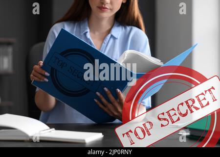 Junge Frau, die im Büro mit streng geheimen Dokumenten arbeitet Stockfoto