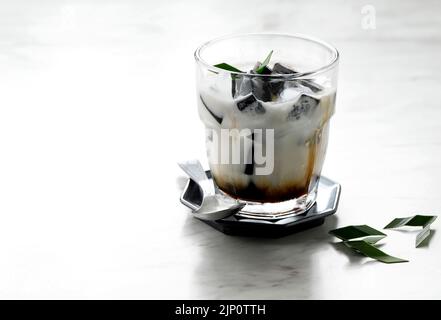 Schwarzgras-Gelee oder Cincau Hitam, indonesisches Dessert aus Cincau Leaf mit Kokosmilch und Palmzucker. Stockfoto