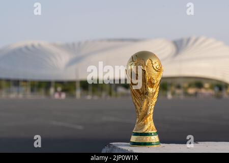 DOHA, KATAR - 14. AUGUST 2022: Trophäe der FIFA-Weltmeisterschaft vor dem Hintergrund des Al Janoub-Stadions in Katar. Stockfoto