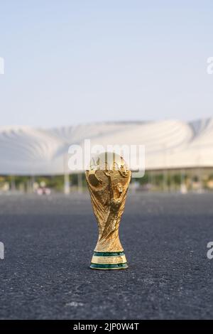 DOHA, KATAR - 14. AUGUST 2022: Trophäe der FIFA-Weltmeisterschaft vor dem Hintergrund des Al Janoub-Stadions in Katar. Stockfoto