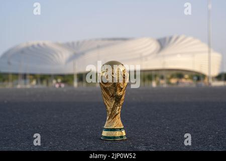 DOHA, KATAR - 14. AUGUST 2022: Trophäe der FIFA-Weltmeisterschaft vor dem Hintergrund des Al Janoub-Stadions in Katar. Stockfoto