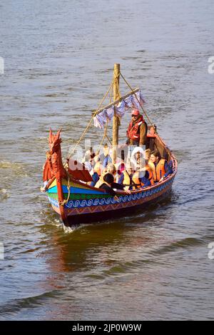 Susdal, Russland, 05.08.2022. Reiten auf dem Fluss Kamenka. Touristen in einem Kreuzschiff in Form eines Wikingerschiffs Stockfoto