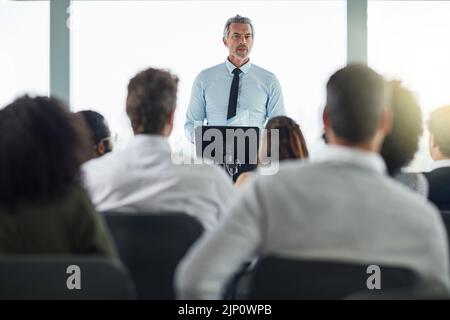 Ein gutaussehender, reifer Geschäftsmann, der auf einer Geschäftskonferenz spricht. Stockfoto