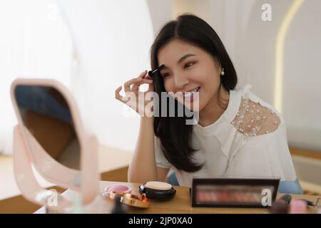Frau mit Kosmetik und versuchen, sich nach ihrem Vlogger zu bilden Stockfoto