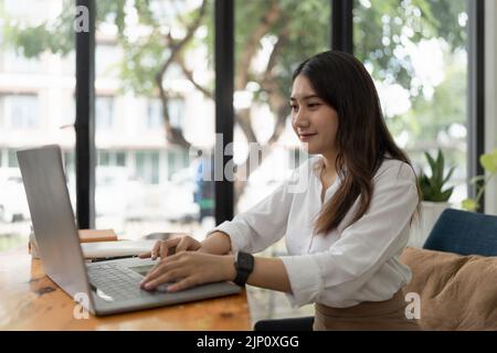 Geschäftsfrau, die während eines Gesprächs mit einem Geschäftspartner einen Videoanruf auf einem Laptop führt Stockfoto