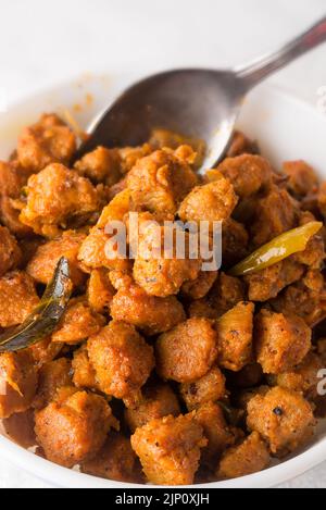 Nahaufnahme von Sojafleischgerichten mit einem Löffel im Hintergrund, vegetarisches, mit Sojabohnennuggets oder Brocken und Gewürzen zurechtgemahlenes, proteinreiches Essen Stockfoto