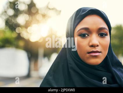 Natürlich und schön. Porträt einer selbstbewussten jungen Frau, die tagsüber draußen auf die Kamera schaut. Stockfoto