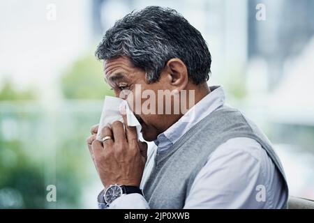 Die Grippesaison steht wieder an. Ein reifer Mann bläst seine Nase. Stockfoto