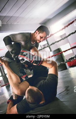 Zwei junge Boxer, die sich in einem trainingssparenden Kampf in einem Boxring auf dem Boden in einem Fitnessstudio gegenüberstehen, sind das, worum es geht Stockfoto