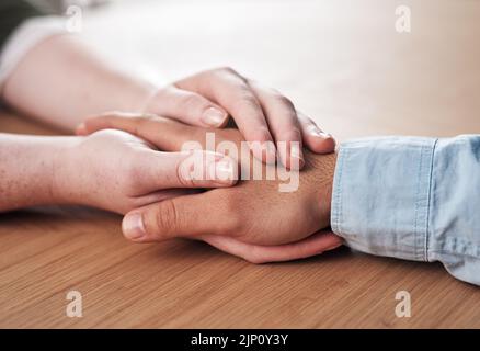 Nichts heilt wie die menschliche Berührung. Ein Mann und eine Frau halten die Hände bequem auf einem Tisch. Stockfoto