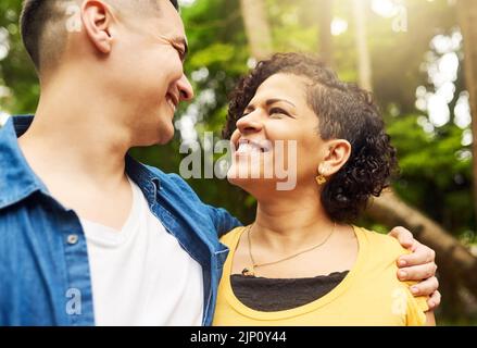 Ich könnte mich in diesen Augen verlaufen. Ein liebevolles junges Paar, das von Angesicht zu Angesicht draußen im Park steht. Stockfoto