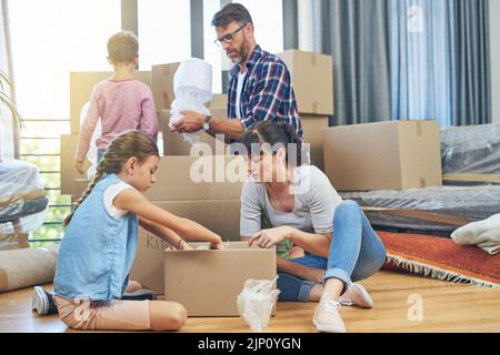 Packen ist nicht nur Mutter und Vater Verantwortung. Eine vierköpfige Familie hilft sich gegenseitig Verpackung Boxen am Umzugstag. Stockfoto