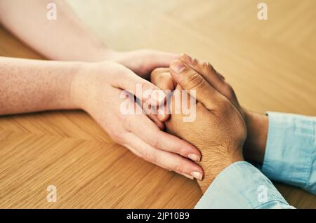 Nichts heilt wie die menschliche Berührung. Ein Mann und eine Frau halten die Hände bequem auf einem Tisch. Stockfoto