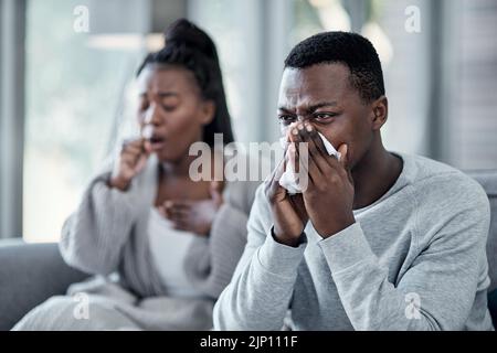 Grippe, Erkältung oder krankes Paar mit Covid Husten, Niesen und Blasen ihre Nase mit einem Gewebe, während in Isolation zusammen zu Hause im Winter. Jung Stockfoto