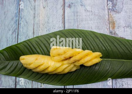 Zwei in Scheiben geschnittene gelbe Ananas auf Blatt serviert Stockfoto