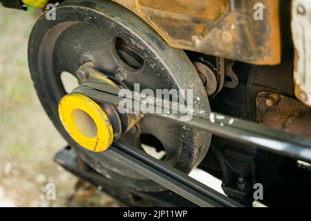 Der Motor eines Gartenfahrtraktors aus der Nähe. Gelbe Riemenscheibe, Angetriebenes Drehmomentgetriebe Stockfoto