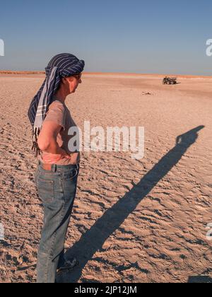 Botswana Afrika - August 29 2007; in der Wüste stehende Touristenfrau wirft einen langen Schatten in Sicht und wartet darauf. Stockfoto
