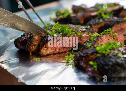 Nahaufnahme des auf einer Aluminiumfolie geschnittenen, kohlbekohlten Steaks Stockfoto