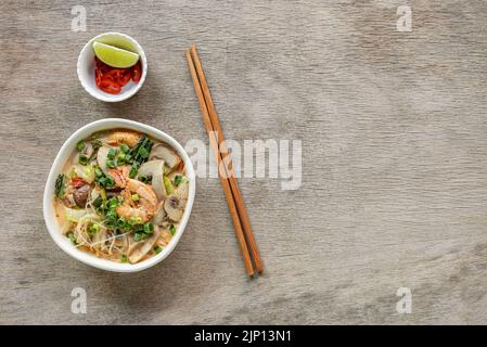 Eine typische Schüssel mit einem in Südostasien beliebten, würzigen Nudelgericht aus Glas, einer Laksa-Schale. Stockfoto