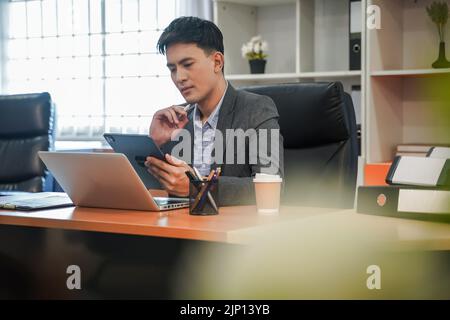 Geschäftsmann, der in einem Tablet-Büro denkt, kaukasisch aussehende mobile Kollegen auf dem Bildschirm Stockfoto