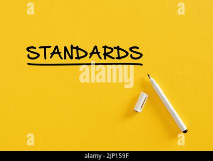 Das Wort Standards auf gelbem Hintergrund mit Filzstift geschrieben. Regeln, Verfahren und Standardisierung in Geschäfts- oder Bildungsprozessen. Stockfoto