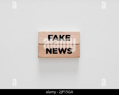 Das Wort Fake News auf Holzblöcken auf weißem Hintergrund. Stockfoto