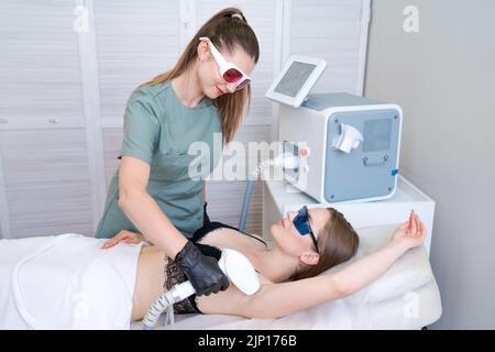 Lasermaschine. Junge Frau, die Laserbehandlung erhält. Hautpflege. Kaukasisches Mädchen, das Gesichtsbehandlungen erhält und Pigmentflecken in einer Kosmetikklinik entfernt. Fotografische Therapie. Stockfoto