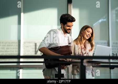 Glückliche junge Geschäftsleute, die im Freien chatten und digitale Geräte nutzen Stockfoto