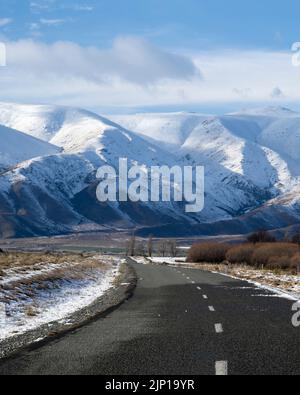 Lake Ohau Road, die in Richtung schneebedeckter Bergketten führt, Twizel, South Island.Vertikales Format. Stockfoto